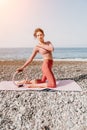 Woman sea pilates. Sporty happy middle aged woman practicing fitness on beach near sea, smiling active female training Royalty Free Stock Photo