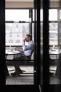 Middle aged white businessman drinking coffee and working alone in a meeting room, vertical Royalty Free Stock Photo