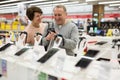 Middle aged wife and husband picking new smartphone in electronic store Royalty Free Stock Photo