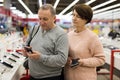 Middle aged wife and husband picking new smartphone in electronic store Royalty Free Stock Photo