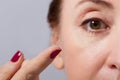 Middle aged woman applying or putting contact lens for vision in her brown eye by finger. Close up and isolated. Selective focus Royalty Free Stock Photo