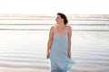 A middle aged woman on the beach with a blue dress