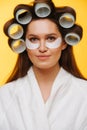 Middle aged woman in a beauty salon sits with hair in rollers and eye patches Royalty Free Stock Photo