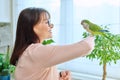 Middle aged woman bird owner holding green quaker parrot on hand