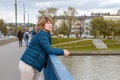 Middle-aged woman with blond hair, European woman standing in a jacket on the bridge and looking at the river,