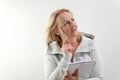 Middle-aged woman blonde writes on notebook with pen glasses in gold frames in studio checking eyesight falling links