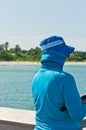 Middle aged woman in blue hat and cloths, fishing from wood pier Royalty Free Stock Photo