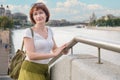 Middle-aged woman with brown hair stands on embankment against the background of the urban landscape Royalty Free Stock Photo