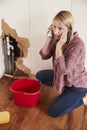Middle aged woman with burst pipe phoning for help, vertical