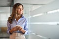 Middle aged woman business investor using phone standing in office looking away. Royalty Free Stock Photo