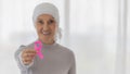 Middle-aged woman cancer patient lost hair from chemo cure process and use clothe cover her head holding pink ribbon the symbol of