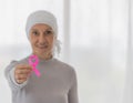 Middle-aged woman cancer patient lost hair from chemo cure process and use clothe cover her head holding pink ribbon the symbol of