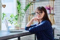 Middle-aged woman at coffee shop drinking coffee, with laptop, looking at camera Royalty Free Stock Photo