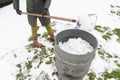 middle-aged woman is collecting snow in a barrel with a shovel,natural resources