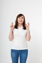 Middle aged woman crossing her fingers and wishing for good luck. Blank white t-shirt, mock up. Fashion outfit with tshirt Royalty Free Stock Photo