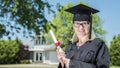 Middle aged woman with diploma in hand. Wearing a graduate uniform