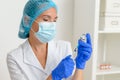 A middle-aged woman doctor picks up a syringe from an ampoule containing the covid-19 coronavirus vaccine. Close-up.