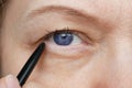 Middle-aged woman does corrective eye makeup to correct the drooping eyelid. Ptosis is a drooping of the upper eyelid, lazy eye. Royalty Free Stock Photo