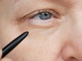 Middle-aged woman does corrective eye makeup to correct the drooping eyelid. Ptosis is a drooping of the upper eyelid, lazy eye. Royalty Free Stock Photo