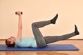 Middle-aged woman doing pilates exercises on the mat at home