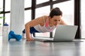 Middle-aged woman doing push-ups at home in front of a laptop monitor Royalty Free Stock Photo