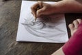 A middle-aged woman draws with a pencil on white paper