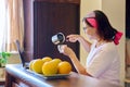 Middle aged woman drinking coffee talking on video call using laptop, kitchen at home Royalty Free Stock Photo