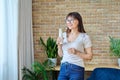 Middle aged woman drinking fermented milk product from bottle, near window