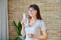 Middle aged woman drinking fermented milk product from bottle, near window