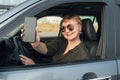 Middle-aged woman driving a car holds out her smartphone and smiles Royalty Free Stock Photo