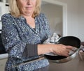 Middle-aged Woman Drying a Frying Pan with a Tea-towel. Royalty Free Stock Photo