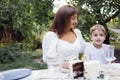 Middle-aged woman in elegant white dress and cute boy at festive table outdoors Royalty Free Stock Photo