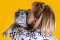 Middle aged woman embracing and kissing beautiful young French Bulldog of unusual grey merle spotted color.