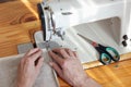 Middle aged woman hands sewing linen cloth on stitching machine, from above overhead top view