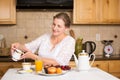 Middle aged woman having breakfast in a kitchen Royalty Free Stock Photo