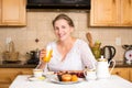 Middle aged woman having breakfast in a kitchen Royalty Free Stock Photo