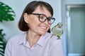 Middle aged woman at home with a pet parrot on her shoulder Royalty Free Stock Photo