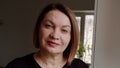 a middle-aged woman looks at the camera and has mixed emotions close up