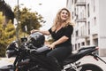 middle aged woman in motorbiker clothing riding a motorcycle outdoors