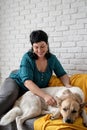 Middle aged woman patting her shepherd dog on the sofa at home Royalty Free Stock Photo