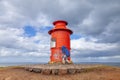 middle aged woman photographer take a shot with camera in front of a red lighthouse Royalty Free Stock Photo