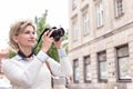 Middle-aged woman photographing through digital camera in city