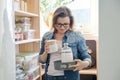 Middle-aged woman picking food from storage cabinet in kitchen Royalty Free Stock Photo