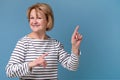 Middle aged woman pointing at copyspace isolated on blue background Royalty Free Stock Photo