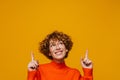 Middle-aged woman pointing fingers up at copyspace isolated over yellow background Royalty Free Stock Photo