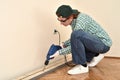 Middle-aged woman using electric drill to make a hole in the wooden plank