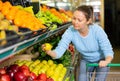 Middle-aged woman purchaser buying fresh apples in grocery store