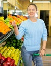 Middle-aged woman purchaser buying fresh tangerines in grocery store