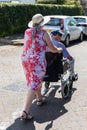 A middle aged woman pushing an elderly man in a wheelchair
