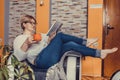 Middle aged woman reading book and drinking coffee at home Royalty Free Stock Photo